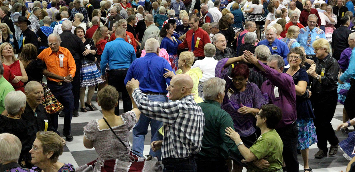 A large gathering of square dancers on a festival dance floor