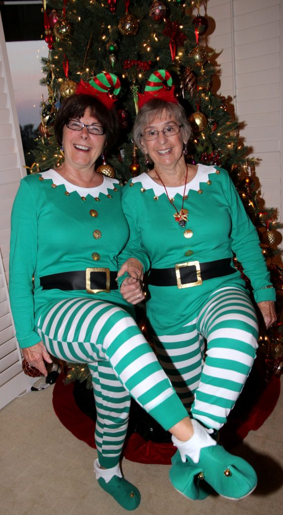 Two club members dressed as Christmas elves beside a Christmas tree