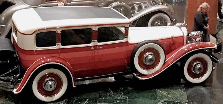 A vintage red and white car on display at the Nethercutt Museum